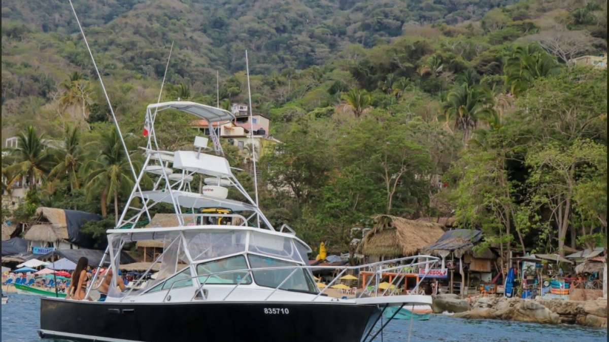 Guests swimming from a private charter boat anchored off a beach in Banderas Bay
